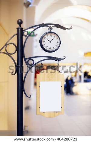 Clock with empty advertising board inside the building