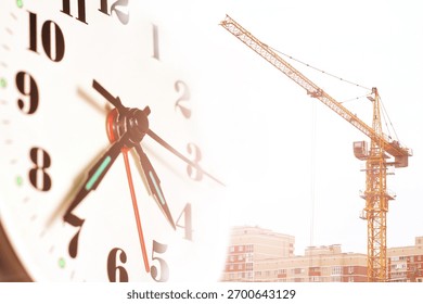 A clock face and a construction tower crane. Construction time.