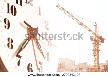A clock face and a construction tower crane. Construction time.