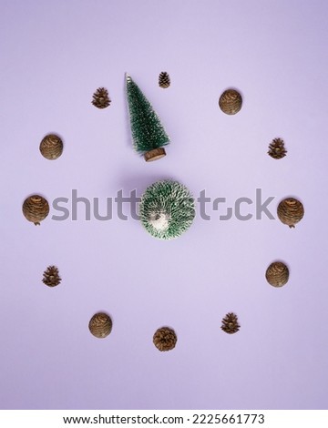 Clock face made of pine cone and Christmas tree on pastel purple background. Creative countdown for New Year. Minimal flat lay winter concept. Winter holiday season.