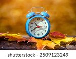 Clock with fallen leaves are on the bench 