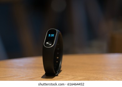 A Clock Of Fitness Smart Band Device On Wooden Table