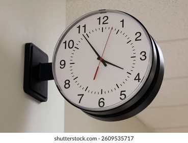 Clock hanging on the side of a wall at a school, hospital, or office