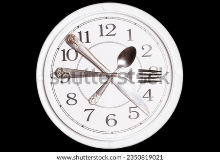 Clock made of knife, spoon and fork on black background.