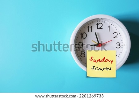 Clock on blue copy space background with stick note SUNDAY SCARIES (Sunday blues) - feelings of intense anxiety or dread nervousness happen on night before head back to work, office or school 