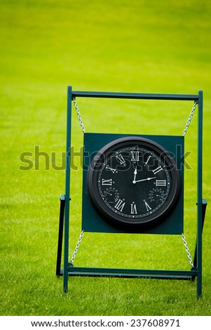 Clock on golf course with green spring valley on the background