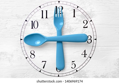 the clock on the table where is the arrow plastic fork and a plastic spoon. plastic utensils and click on the table. the concept of diet and health