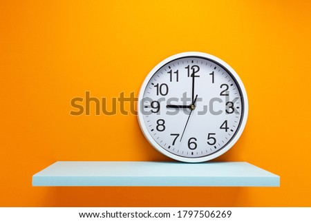 clock and shelf at wall background surface