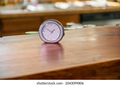 Clock Sits On Wooden Counter With Kitchen Background. No People. High Quality Photo