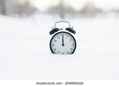 The clock in the snow shows the time at 12 o'clock. winter coming soon concept.