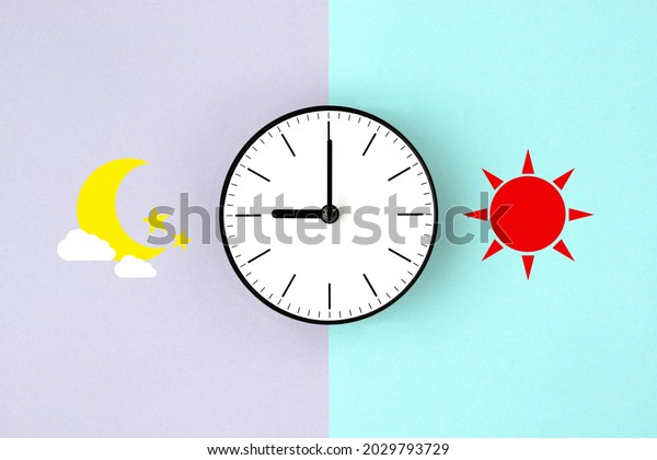 Clock with sun and moon pictogram on two\
colors background, time management\
image