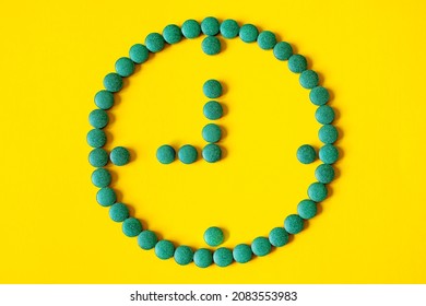 A clock symbol made from tablets on a yellow background. 9 o'clock on the clock face. Medication regimen, treatment regimen - Shutterstock ID 2083553983