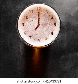 Clock Symbol On Foam In Beer Glass On Black Table, View From Above