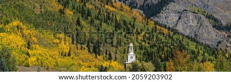 The clock tower of the county courthouse with a bockground of colorful aspen trees in Selverton, Colorado
