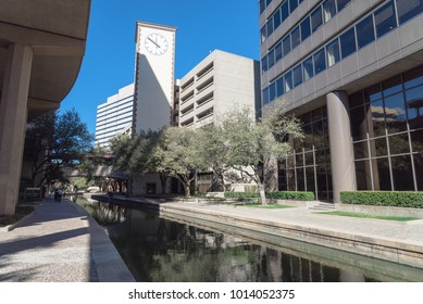 Clock tower and elevated apt light rail guide way alongside Mandalay Canal Walk in Las Colinas, Irving, Texas. Winding canal walkway along tree-lined path, peaceful and stirring Old World style.