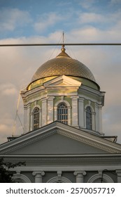 A clock tower in front of a building. High quality photo, dome of the orthodox church. golden color, the building is painted blue. the sky is a soft blue color with clouds
