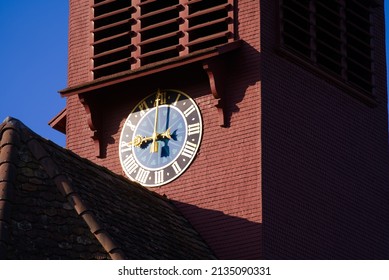Clock tower of protestant church at Laufen-Uhwiesen on a sunny spring day. Photo taken March 5th, 2022, Laufen-Uhwiesen, Switzerland.