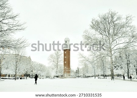 Clock tower and trees in the snow on a university campus