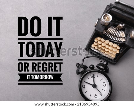 Clock and typewriter with text DO IT TODAY OR REGRET IT TOMORROW on gray background.