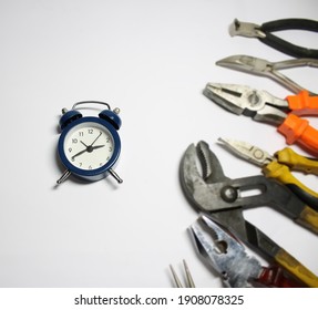 Clock And Various Pliers On A White Surface