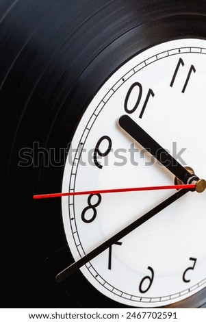 Clock vinyl record plate, arrow, backward time close-up.