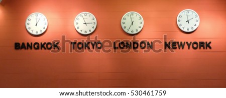 Clocks on a Orange a wall, Four wall clocks showing time in different capitals of the world, selective focus, soft focus