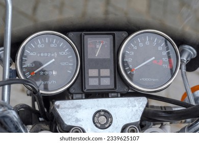 "Clocks" of a parked motorcycle in a retro style. Speedometer, tachometer and odometer on the dashboard of a motorcycle with a plastic fairing.