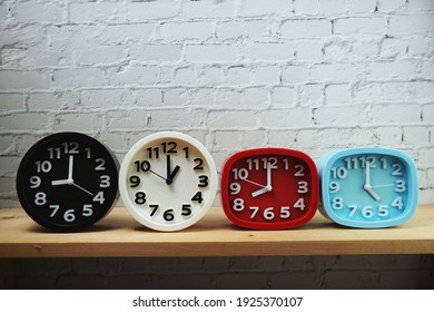 Clocks with time zone of different country on wooden shelves and white brick wall background