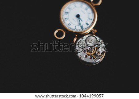 Clockwork mechanism. Clock lying on black background. Close-up photo. Picture for watchmaker. Vintage clocks and details. Steel, metallic parts. Roman numerals. Golden watch. Transience of life. Death