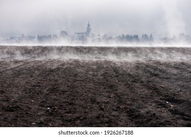Clods of earth in a plowed field in preparation for the next planting, with village silhouette in background.