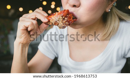 Cloes up of woman holding and eating fries chicken
