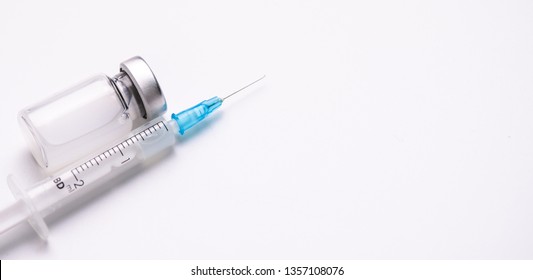 Cloesup of flu, hpv or measles vaccine bottle and syringe with needle on white medical background, medicine and drug concept