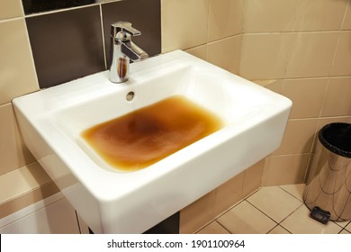 Gepäckiges Waschbecken mit schmutzigem Wasser in einer Cafeteria-Toilette. Blockierprobleme im Badezimmer und Toilette