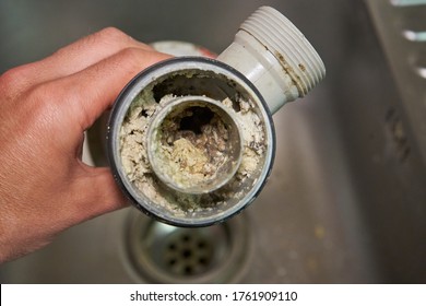 clogged sink pipe,in the hands of a clogged dirty sewer pipe from leftover food - Shutterstock ID 1761909110