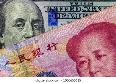 Close up of 100 Yuan banknote  over a one hundred Dollar banknote with focus on portraits of Benjamin Franklin and Mao Tse-tung/USA vs China trade war concept