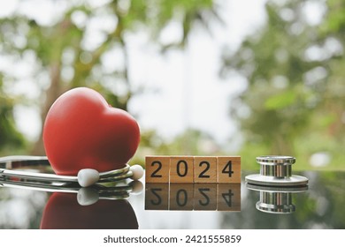 close up 2024 wooden text block, red heart and stethoscope on table, world health day, medical and healthcare, cardiology and cancer crisis risk and problem concept