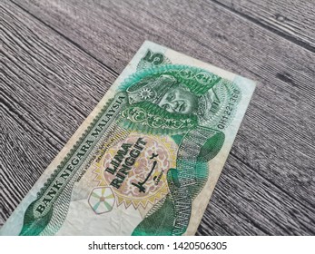 up close of 5 Ringgit Malaysia ( RM ) money on wooden background with selective focus.  