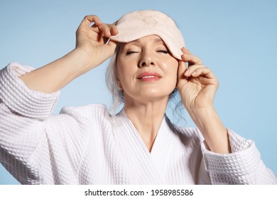 Close Up 50s Calm Mature Female With Sleeping Mask And Closed Eyes Relaxing Enjoying. Bedtime Routine And Beauty Concept. Groomed Good-looking Elderly Woman On Blue Studio Background.