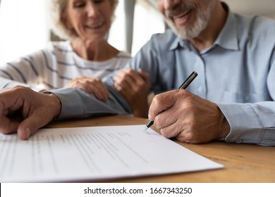 Close up of 60s husband and wife sit at desk sign health insurance contract close deal, smiling old mature couple spouses put signature on document make good agreement, elderly healthcare concept - Powered by Shutterstock