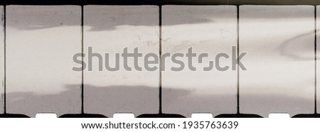 close up of 8mm movie filmstrip isolated on white background with light reflection, old scratched homemovie film material.
