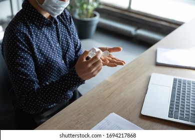 Close up above view responsible cautious young indian female employee in medical mask sanitizing hands with alcohol-based antiseptic liquid, keeping doing safety hygienic routine against coronavirus. - Shutterstock ID 1694217868