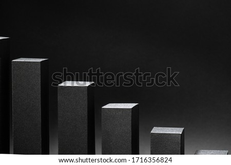 Close up of an abstract declining 3d bar chart made from black colored paper. Over dark background