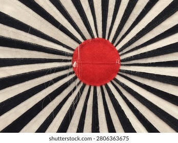 close up of an abstract radial pattern in black and white with a striking red center that resembles the shape of a shining sun