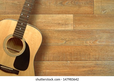 Close up of an acoustic guitar on a wooden floor, shot from above - Powered by Shutterstock