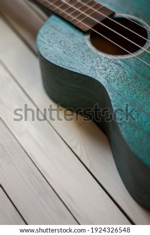 Close up of acoustic ukulele; ukulele strings, saddle, soundhole, ukulele body, neck, fretboard. Fretted folk instrument, wooden, inlay.