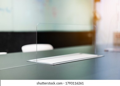 Close Up Of Acrylic Plexiglass Separator Standing Partition Wall With Pass-through On The Desk In The Meeting Room. Social Distancing In Offices During The Covid-19 Pandemic. Precaution And Safe.