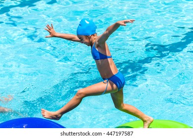 Close up action shot of kid running on inflatable mattress in swimming pool. - Powered by Shutterstock