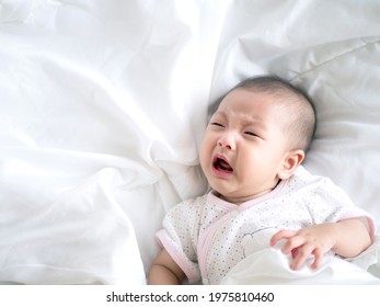 Close up Adorable Asian baby infant girl cry on a white bed , colic symptom or hungry unhappy of infant concept - Powered by Shutterstock