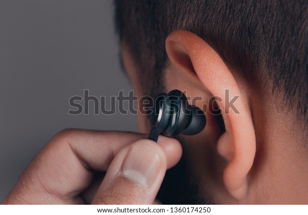 close up of adult caucasian male with earphones in\
the ear