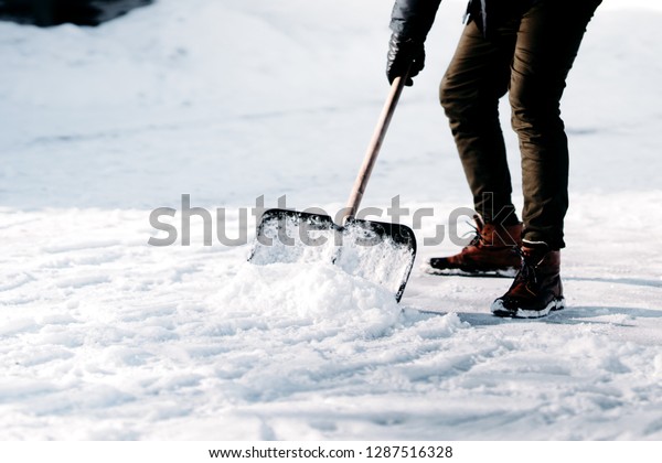 close up of adult cleaning snow from\
sidewalk and using snow shovel after heavy\
snowstorm